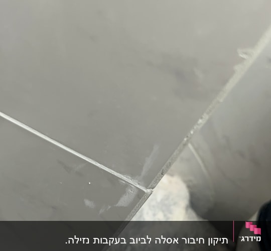 צינור פלסטיק מחובר לקיר עם אריחים אפורים